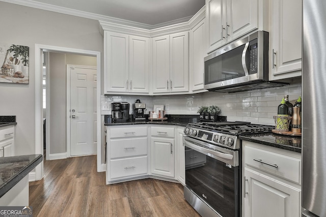 kitchen with white cabinetry, stainless steel appliances, dark stone countertops, dark hardwood / wood-style floors, and ornamental molding