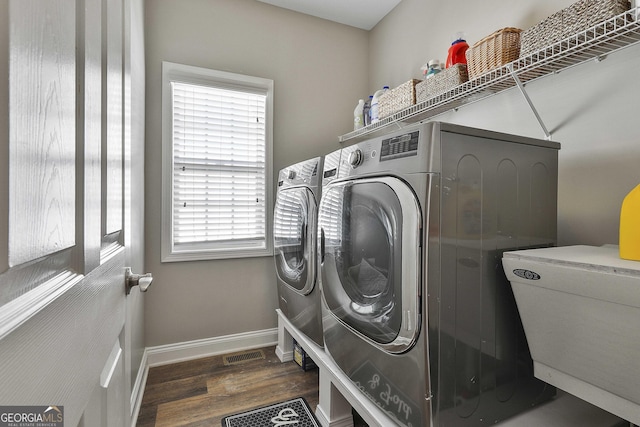 clothes washing area with dark wood-type flooring, a wealth of natural light, and washer and clothes dryer