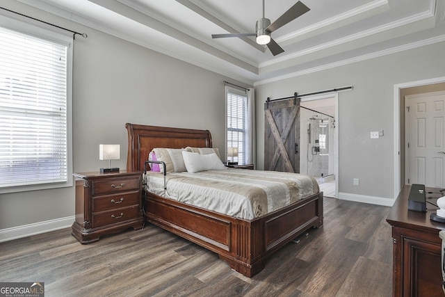 bedroom featuring ceiling fan, a barn door, crown molding, a tray ceiling, and dark wood-type flooring