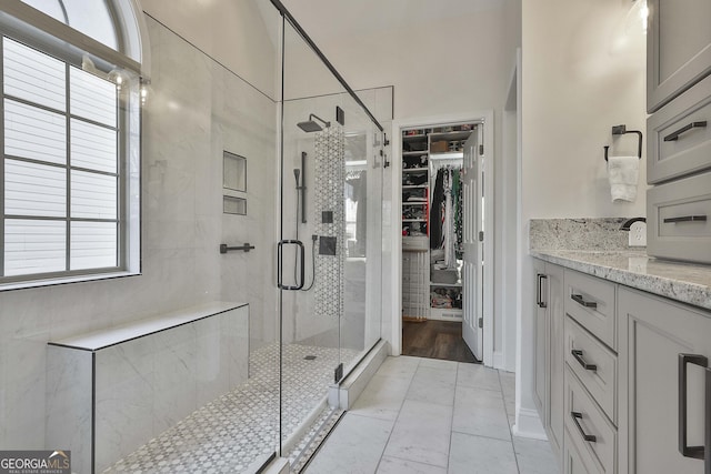 bathroom featuring a shower with shower door and vanity