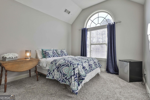 carpeted bedroom with multiple windows, stainless steel fridge, and lofted ceiling