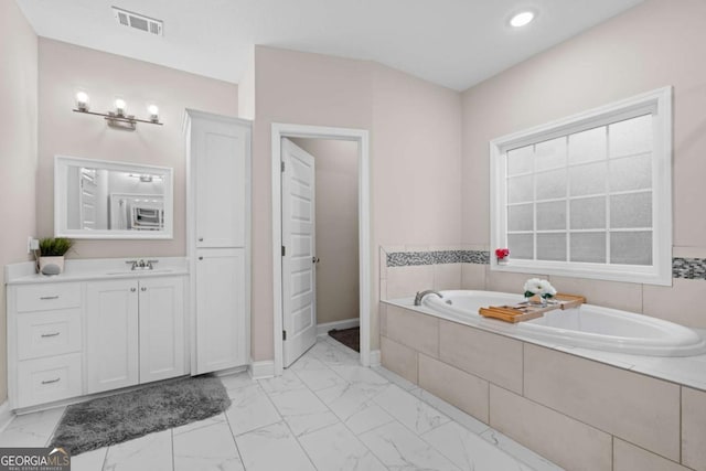 bathroom with vanity and tiled tub