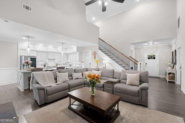 living room with sink, hardwood / wood-style flooring, ceiling fan, a towering ceiling, and ornamental molding