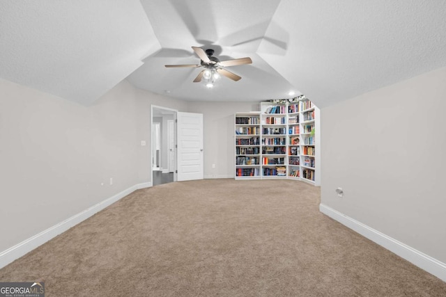 interior space with a textured ceiling, carpet floors, ceiling fan, and lofted ceiling