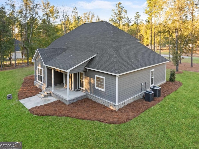 rear view of property with a yard, a patio, and central AC