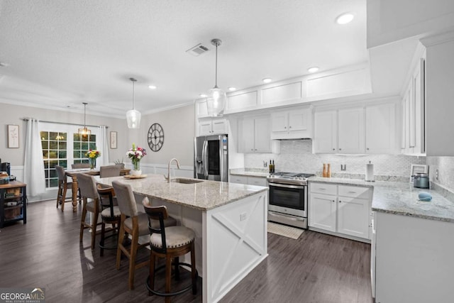 kitchen with appliances with stainless steel finishes, sink, a center island with sink, decorative light fixtures, and white cabinets