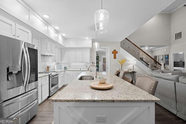 kitchen with stainless steel appliances, hanging light fixtures, a center island with sink, and sink