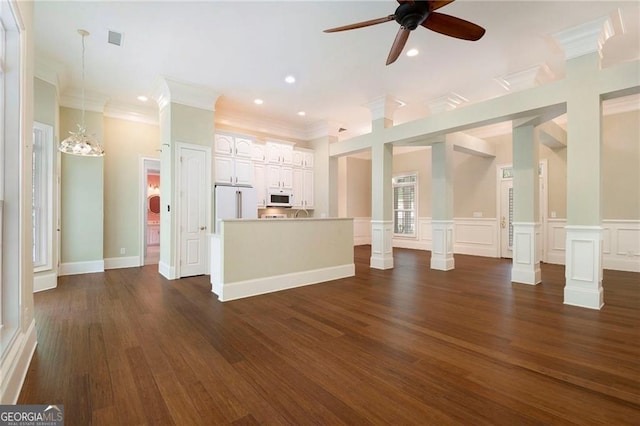 unfurnished living room with ceiling fan with notable chandelier, dark hardwood / wood-style flooring, ornamental molding, and decorative columns