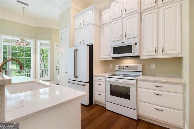 kitchen with light stone countertops, white appliances, sink, decorative light fixtures, and white cabinets