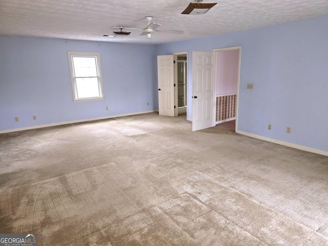 spare room featuring light carpet, ceiling fan, and a textured ceiling