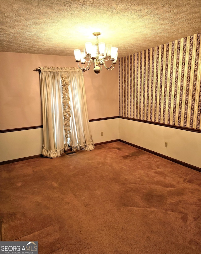 spare room featuring carpet, a textured ceiling, and a notable chandelier