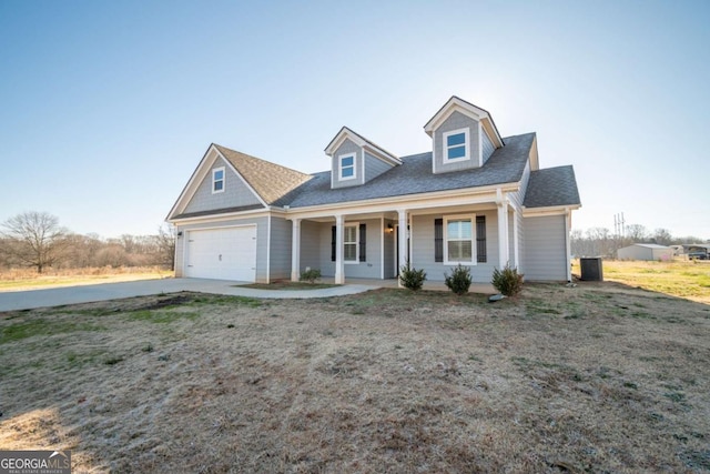 new england style home featuring a porch, a garage, and central AC unit