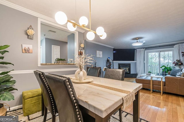 dining room with crown molding, a textured ceiling, and light wood-type flooring