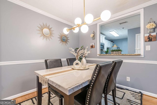 dining space with ornamental molding and light hardwood / wood-style flooring