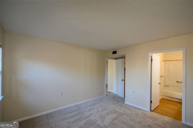 unfurnished bedroom featuring light colored carpet and connected bathroom