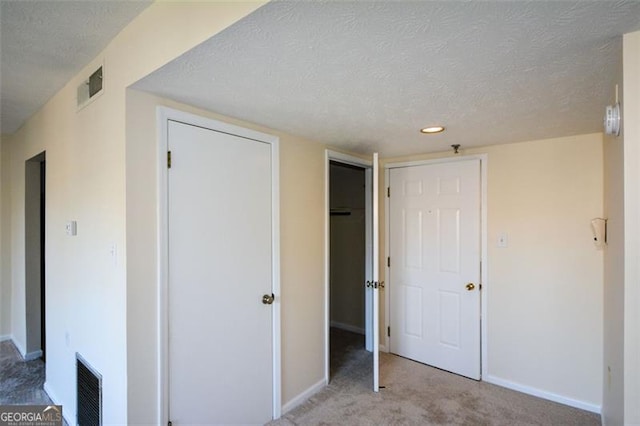 unfurnished bedroom with a textured ceiling and light carpet