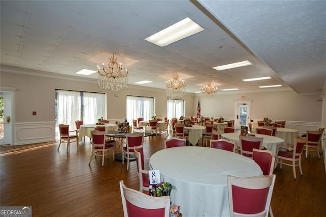 dining space featuring dark hardwood / wood-style flooring, crown molding, and an inviting chandelier