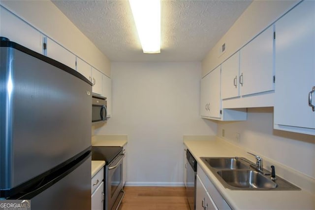 kitchen with white cabinetry, sink, stainless steel appliances, and a textured ceiling