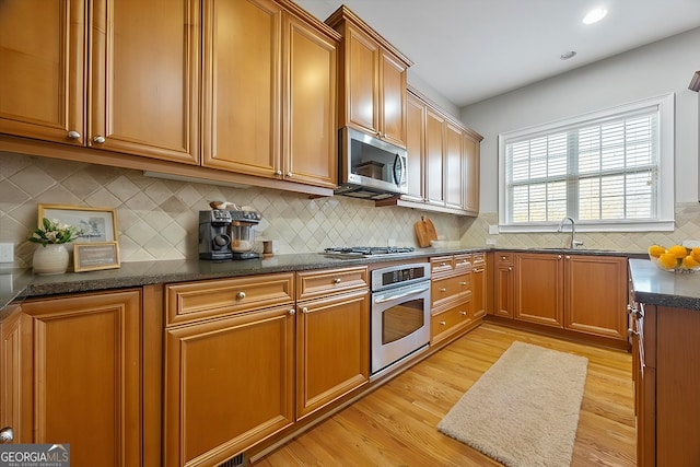 kitchen featuring light hardwood / wood-style floors, sink, appliances with stainless steel finishes, and tasteful backsplash