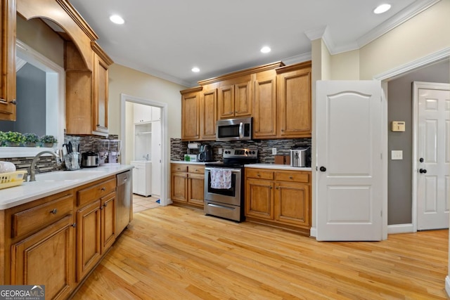 kitchen with sink, stainless steel appliances, tasteful backsplash, crown molding, and light hardwood / wood-style floors