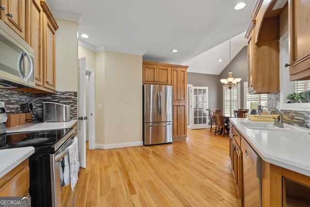 kitchen featuring sink, hanging light fixtures, stainless steel appliances, an inviting chandelier, and light wood-type flooring