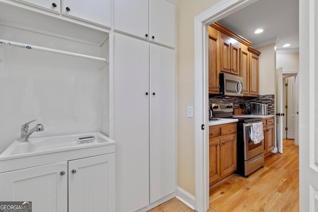 kitchen featuring sink, stainless steel appliances, tasteful backsplash, white cabinets, and ornamental molding