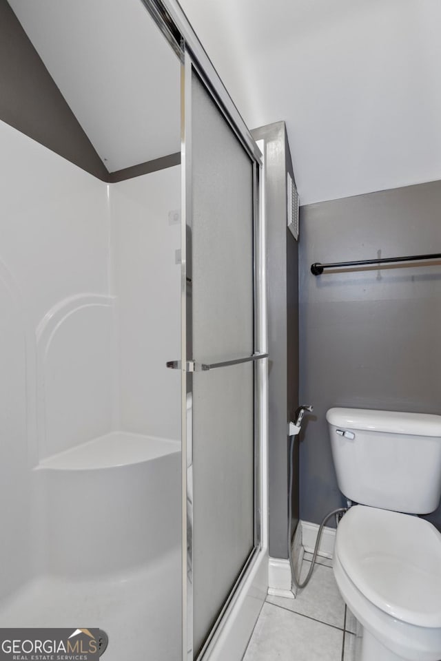 bathroom featuring a shower with door, tile patterned flooring, vaulted ceiling, and toilet