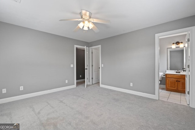 unfurnished bedroom with ensuite bathroom, ceiling fan, light colored carpet, and sink