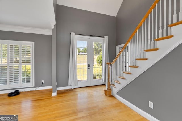 entrance foyer featuring hardwood / wood-style flooring, crown molding, a wealth of natural light, and french doors