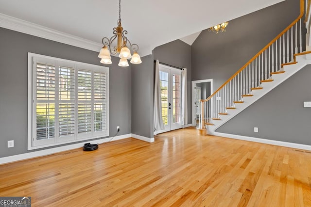 interior space featuring wood-type flooring, french doors, crown molding, and an inviting chandelier