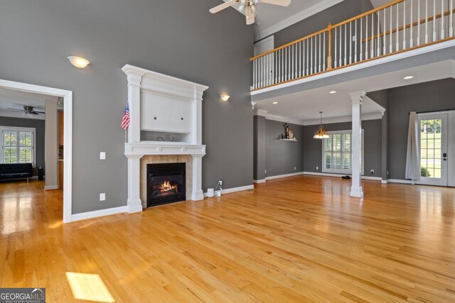 unfurnished living room featuring a tiled fireplace, plenty of natural light, and light hardwood / wood-style floors