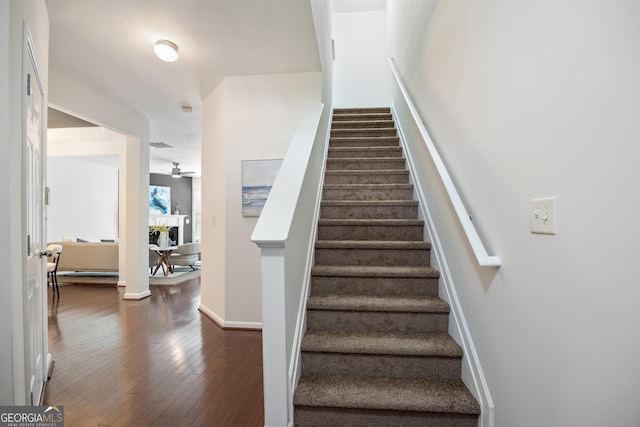 stairs featuring hardwood / wood-style floors and ceiling fan