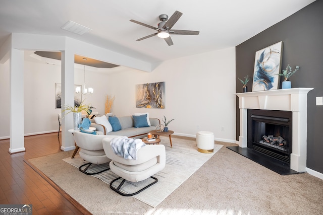 living room featuring beam ceiling, ceiling fan with notable chandelier, and wood-type flooring