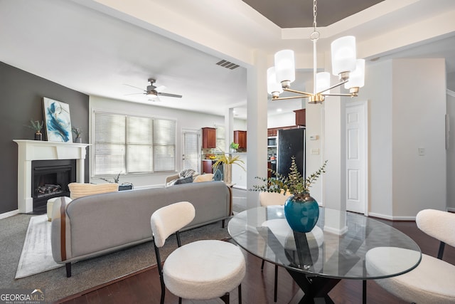 dining space featuring dark hardwood / wood-style flooring and ceiling fan with notable chandelier