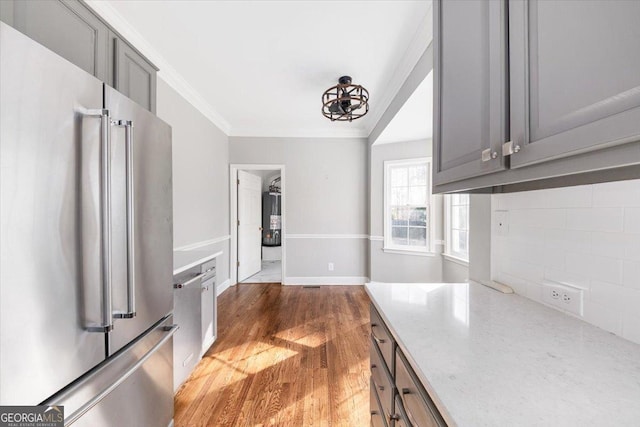 kitchen with gray cabinetry, crown molding, stainless steel appliances, and dark hardwood / wood-style floors