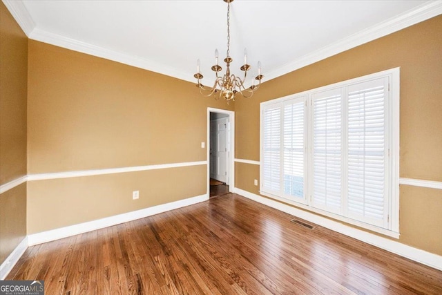 empty room with wood-type flooring, ornamental molding, and a notable chandelier