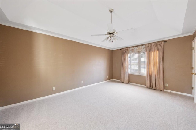 carpeted empty room with a tray ceiling, ceiling fan, and crown molding