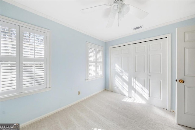 unfurnished bedroom with crown molding, ceiling fan, a closet, and light colored carpet