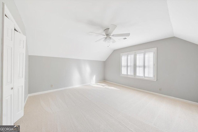 additional living space with ceiling fan, light colored carpet, and lofted ceiling