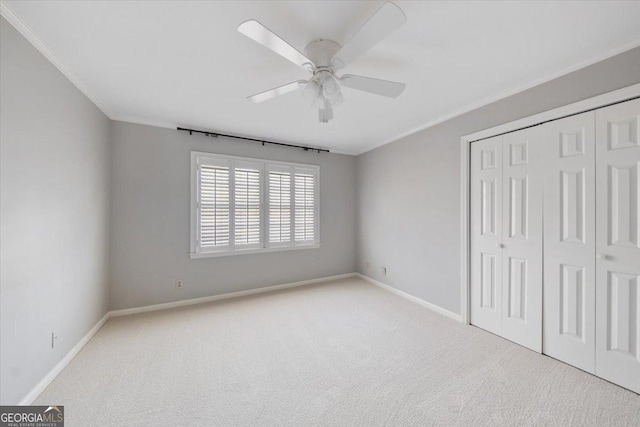 unfurnished bedroom with ceiling fan, a closet, light carpet, and ornamental molding