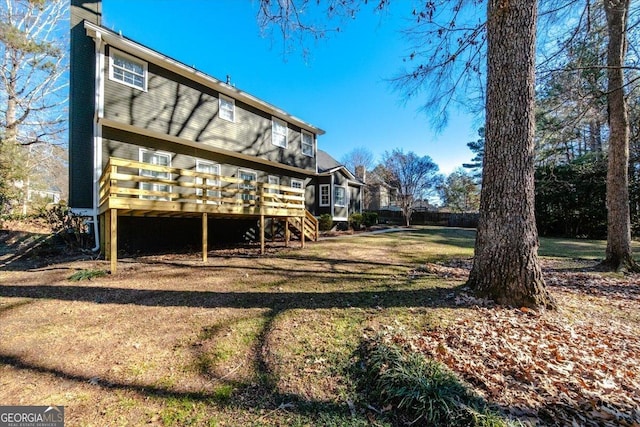 back of property featuring a lawn and a wooden deck