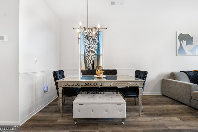 dining space with dark hardwood / wood-style flooring and an inviting chandelier