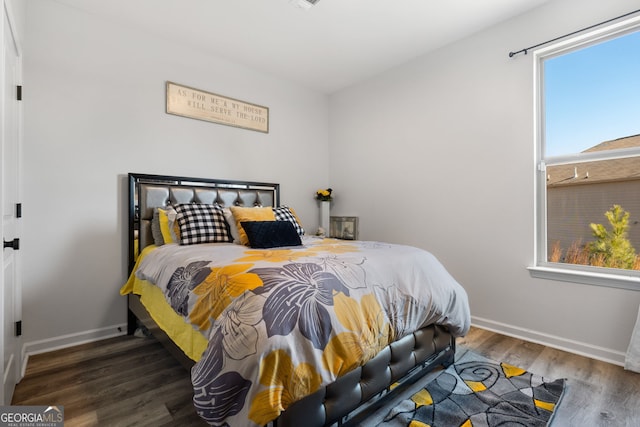 bedroom with multiple windows and dark hardwood / wood-style flooring