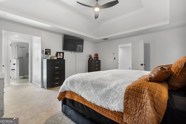 carpeted bedroom with a raised ceiling and ceiling fan