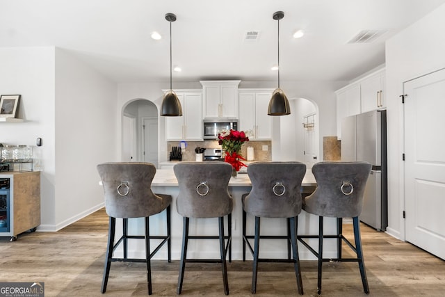 kitchen featuring white cabinetry, a kitchen island, pendant lighting, and appliances with stainless steel finishes