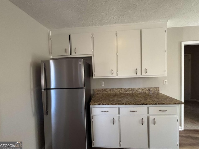 kitchen featuring stainless steel refrigerator, white cabinets, and a textured ceiling