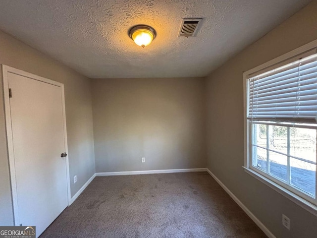 unfurnished room featuring a textured ceiling and carpet floors