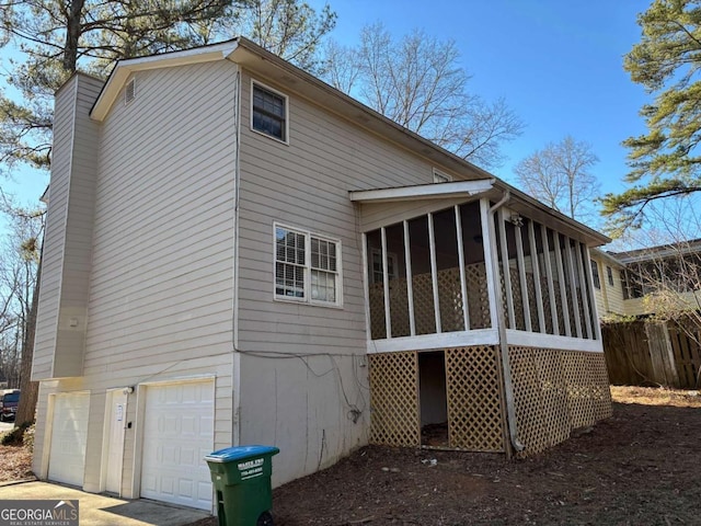 back of property with a garage and a sunroom