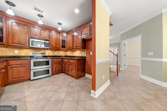 kitchen with decorative backsplash, dark stone counters, ornamental molding, stainless steel appliances, and light tile patterned floors