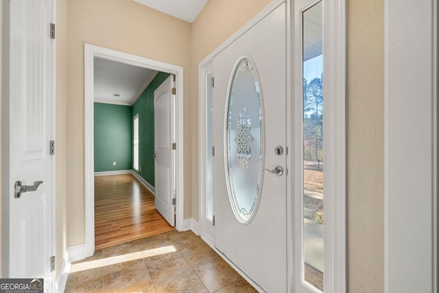 entryway with ornamental molding and light hardwood / wood-style flooring